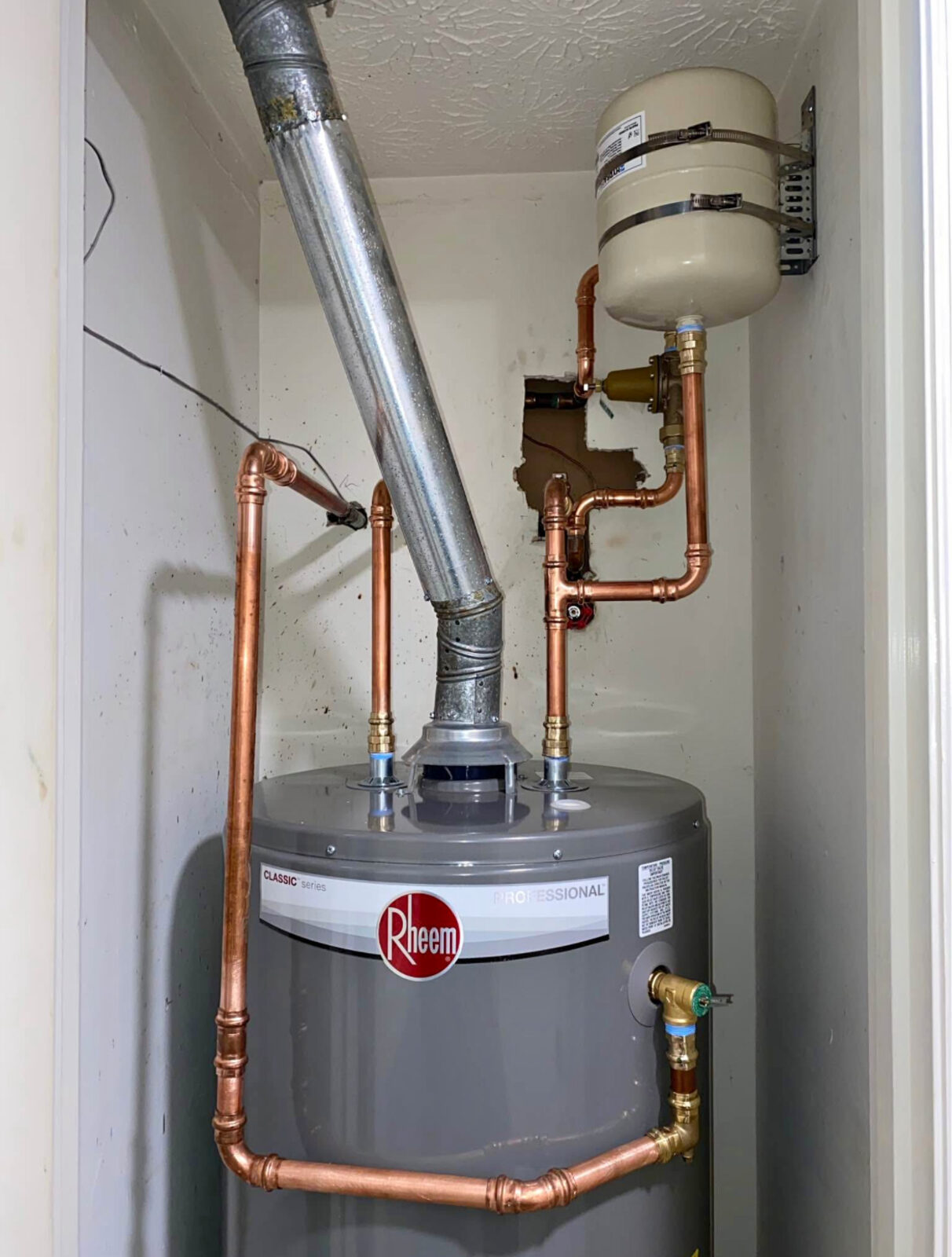 New Rheem Professional water heater installed with fresh copper supply lines, thermal expansion tank, and new flue vent