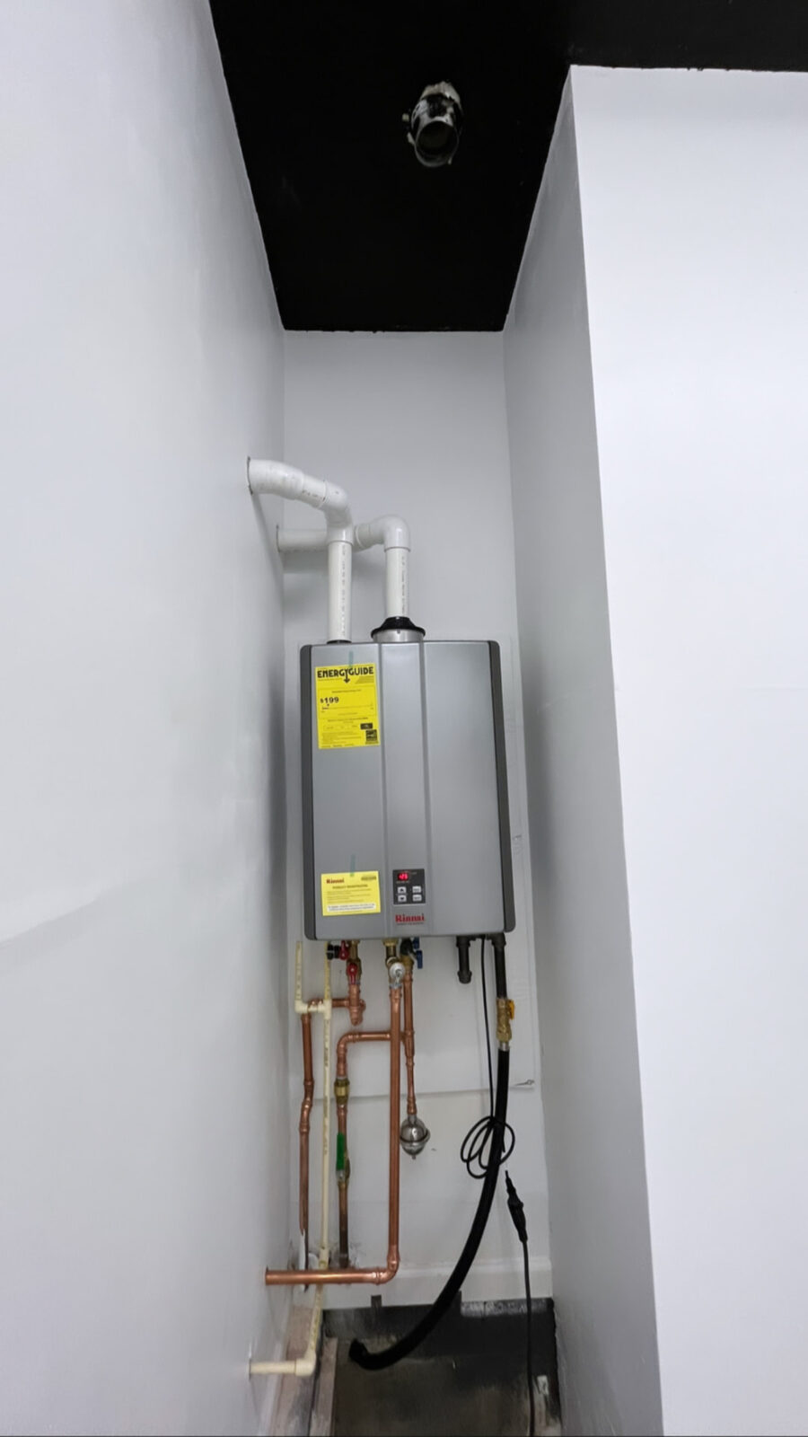 Wall-mounted Rinnai tankless water heater with new PVC venting, copper water lines, and gas connection