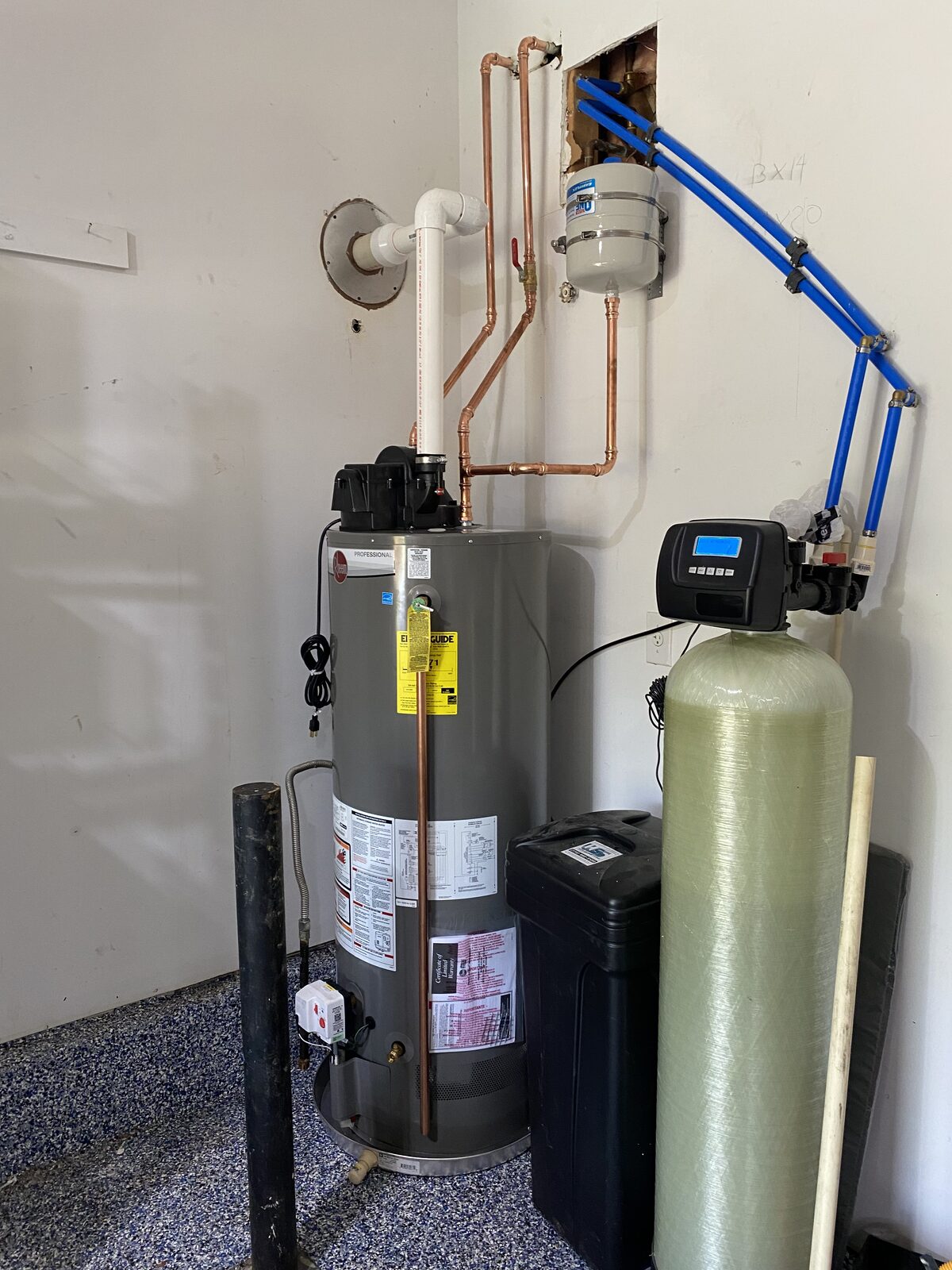 Power-vent water heater installed alongside a new water softener with copper and PEX supply lines in a garage